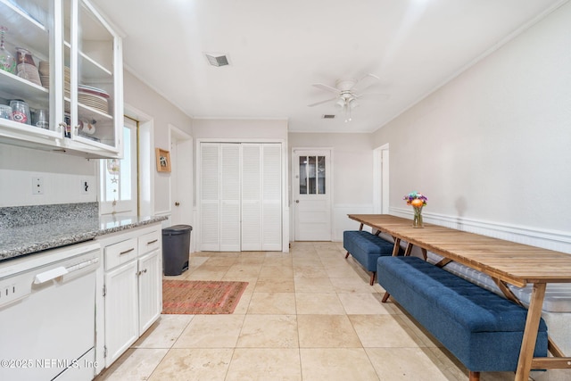2910 Lake Shore Blvd, Jacksonville, FL 32210 - kitchen with white dishwasher, ceiling fan, light stone countertops, white cabinets, and glass insert cabinets