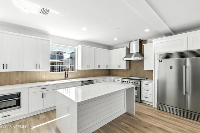 82 Cortez Ave, Saint Augustine, FL 32080 - kitchen featuring high quality appliances, wall chimney exhaust hood, backsplash, light wood-type flooring, and recessed lighting
