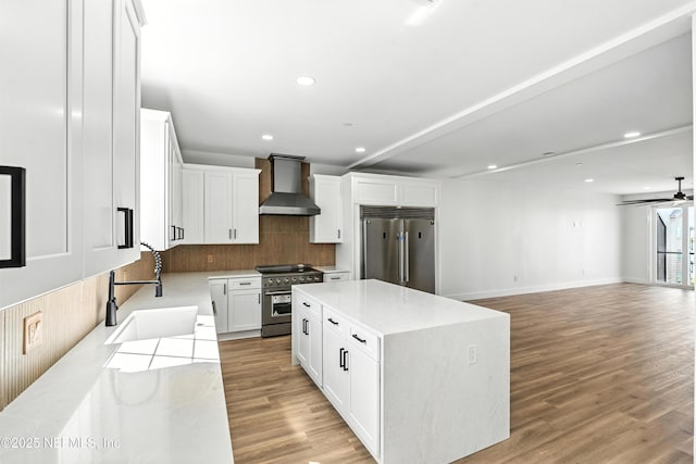 82 Cortez Ave, Saint Augustine, FL 32080 - kitchen with premium appliances, wall chimney range hood, decorative backsplash, light countertops, and light wood finished floors