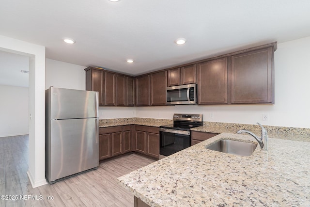 12 Wood Amber Ln, Palm Coast, FL 32164 - kitchen with appliances with stainless steel finishes, dark brown cabinetry, light wood-type flooring, light stone countertops, and recessed lighting