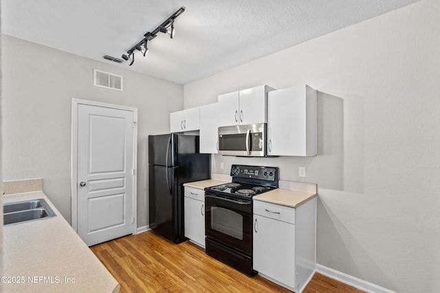 8290 Gate Pkwy Unit 1115, Jacksonville, FL 32216 - kitchen featuring black appliances, rail lighting, light wood-style flooring, light countertops, and white cabinetry