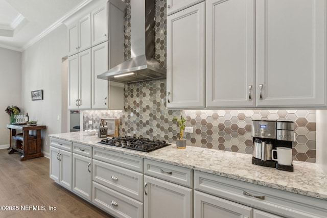 95049 Wild Cherry Dr, Fernandina Beach, FL 32034 - kitchen with wall chimney range hood, stainless steel gas cooktop, ornamental molding, wood finished floors, and decorative backsplash