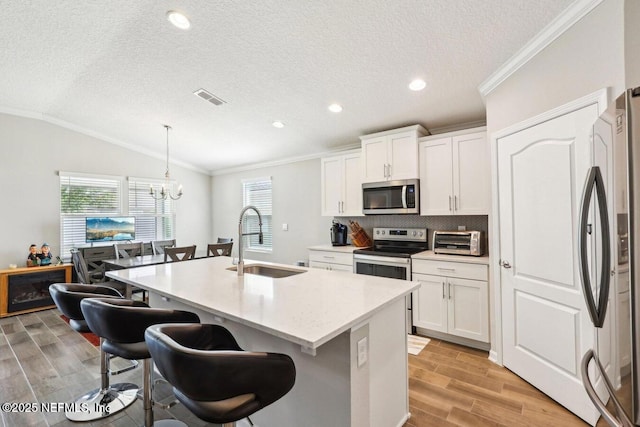 4032 Sandbank Ct, Middleburg, FL 32068 - kitchen featuring stainless steel appliances, vaulted ceiling, a kitchen bar, light wood-type flooring, and a center island with sink
