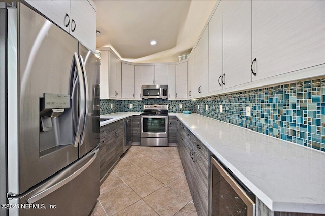 2715 Versailles Ct, Ponte Vedra Beach, FL 32082 - kitchen with stainless steel appliances, beverage cooler, backsplash, light tile patterned floors, and light stone countertops