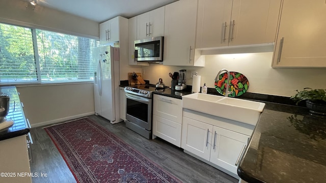 2708 SW 14th Dr Unit 220, Gainesville, FL 32608 - kitchen featuring appliances with stainless steel finishes, white cabinets, dark wood-style floors, and dark countertops