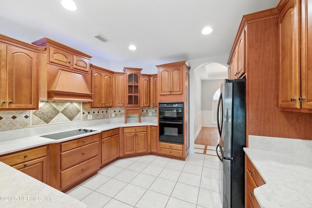 85712 Avant Rd, Yulee, FL 32097 - kitchen featuring black appliances, arched walkways, premium range hood, light countertops, and a wainscoted wall