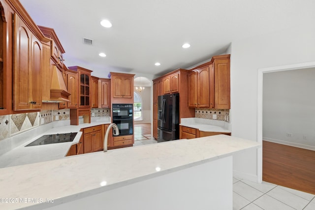 85712 Avant Rd, Yulee, FL 32097 - kitchen with black appliances, backsplash, light tile patterned floors, recessed lighting, and glass insert cabinets