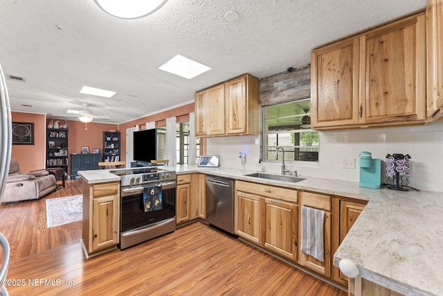 270 Drew St W, Baldwin, FL 32234 - kitchen featuring appliances with stainless steel finishes, a peninsula, a skylight, open floor plan, and light wood-style floors