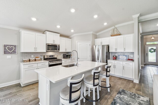 100 Dove Tree Ln, Saint Augustine, FL 32095 - kitchen featuring stainless steel appliances, wood finish floors, tasteful backsplash, a kitchen breakfast bar, and ornamental molding