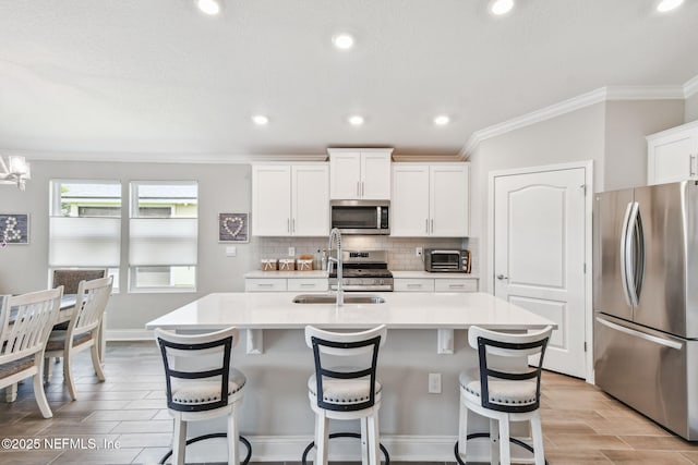100 Dove Tree Ln, Saint Augustine, FL 32095 - kitchen featuring appliances with stainless steel finishes, ornamental molding, light countertops, a center island with sink, and decorative backsplash