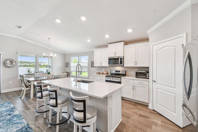 100 Dove Tree Ln, Saint Augustine, FL 32095 - kitchen featuring stainless steel appliances, lofted ceiling, a kitchen island with sink, backsplash, and ornamental molding