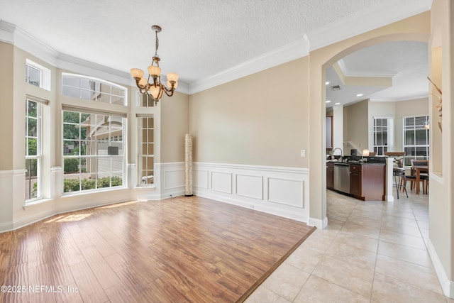 168 Pinehurst Pointe Dr, Saint Augustine, FL 32092 - unfurnished dining area with arched walkways, crown molding, a chandelier, light tile patterned floors, and wainscoting
