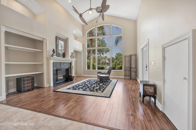 168 Pinehurst Pointe Dr, Saint Augustine, FL 32092 - living room featuring a ceiling fan, a tiled fireplace, high vaulted ceiling, built in features, and wood finished floors