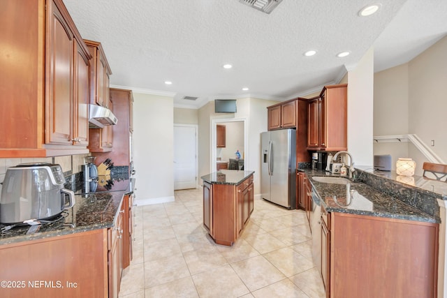 168 Pinehurst Pointe Dr, Saint Augustine, FL 32092 - kitchen with stainless steel fridge with ice dispenser, under cabinet range hood, a center island, dark stone countertops, and ornamental molding