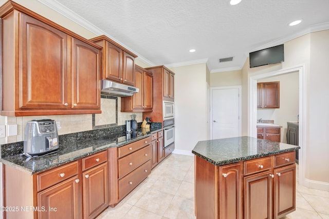 168 Pinehurst Pointe Dr, Saint Augustine, FL 32092 - kitchen featuring under cabinet range hood, oven, white microwave, backsplash, and dark stone counters