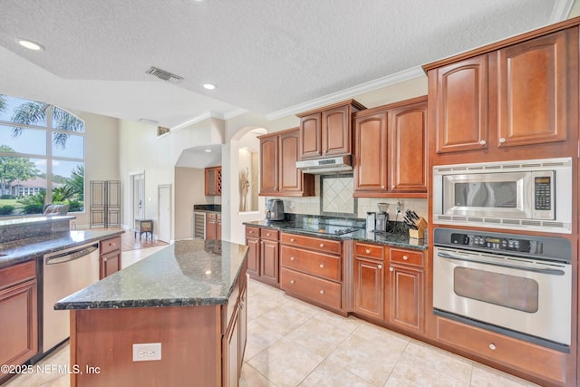 168 Pinehurst Pointe Dr, Saint Augustine, FL 32092 - kitchen featuring appliances with stainless steel finishes, crown molding, backsplash, a textured ceiling, and arched walkways