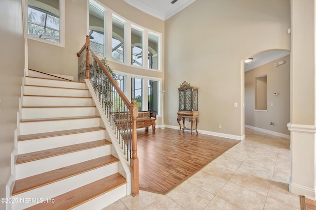168 Pinehurst Pointe Dr, Saint Augustine, FL 32092 - stairway featuring crown molding, arched walkways, tile patterned floors, and a towering ceiling