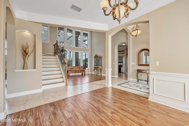 168 Pinehurst Pointe Dr, Saint Augustine, FL 32092 - foyer entrance with arched walkways, a chandelier, crown molding, light tile patterned flooring, and stairs