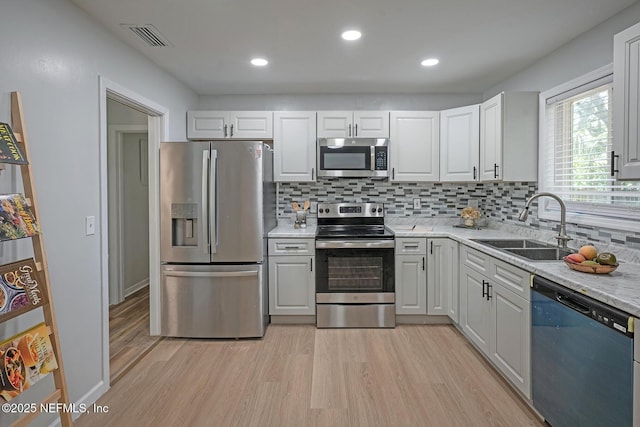5619 Oliver St, Jacksonville, FL 32211 - kitchen with stainless steel appliances, light wood-style flooring, tasteful backsplash, white cabinetry, and recessed lighting