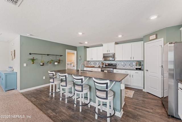 197 Jarama Cir, Saint Augustine, FL 32084 - kitchen with appliances with stainless steel finishes, dark countertops, a breakfast bar, dark wood-style flooring, and a textured ceiling