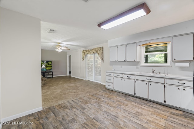 136 Hollywood Forest Dr, Fleming Island, FL 32003 - kitchen featuring light countertops, white cabinetry, light wood-style floors, and a ceiling fan