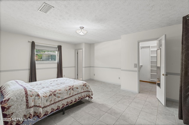 136 Hollywood Forest Dr, Fleming Island, FL 32003 - bedroom featuring a walk in closet, light tile patterned flooring, and a textured ceiling