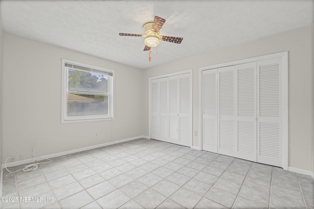 136 Hollywood Forest Dr, Fleming Island, FL 32003 - unfurnished bedroom featuring multiple closets, a textured ceiling, a ceiling fan, and light tile patterned flooring