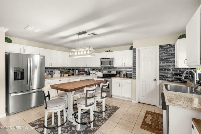 15316 Perdido Dr, Orlando, FL 32828 - kitchen featuring stainless steel appliances, tasteful backsplash, light tile patterned floors, and white cabinets