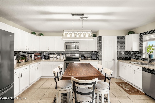 15316 Perdido Dr, Orlando, FL 32828 - kitchen featuring stainless steel appliances, backsplash, light tile patterned floors, and white cabinetry