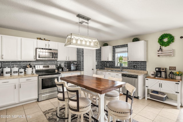 15316 Perdido Dr, Orlando, FL 32828 - kitchen with stainless steel appliances, tasteful backsplash, light tile patterned floors, and white cabinets