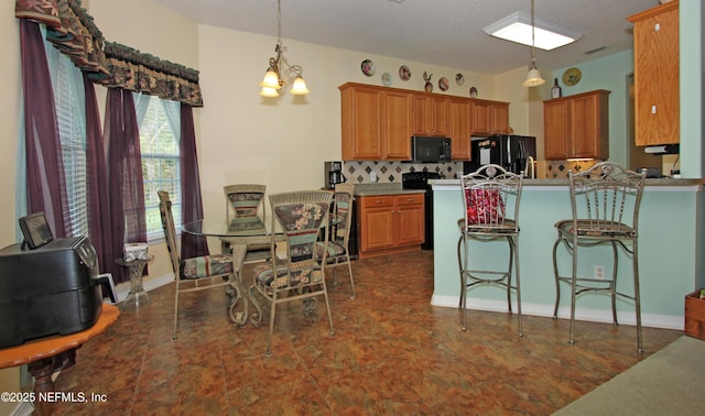 54002 Evergreen Trl, Callahan, FL 32011 - kitchen featuring black appliances, hanging light fixtures, brown cabinets, a kitchen breakfast bar, and a peninsula