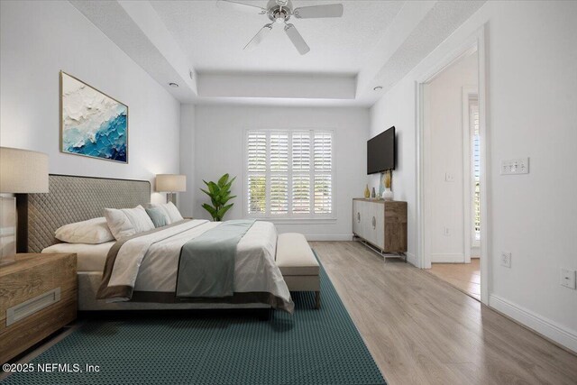 4300 S Beach Pkwy Unit 1206, Jacksonville Beach, FL 32250 - bedroom featuring a raised ceiling, light wood-style flooring, and a ceiling fan
