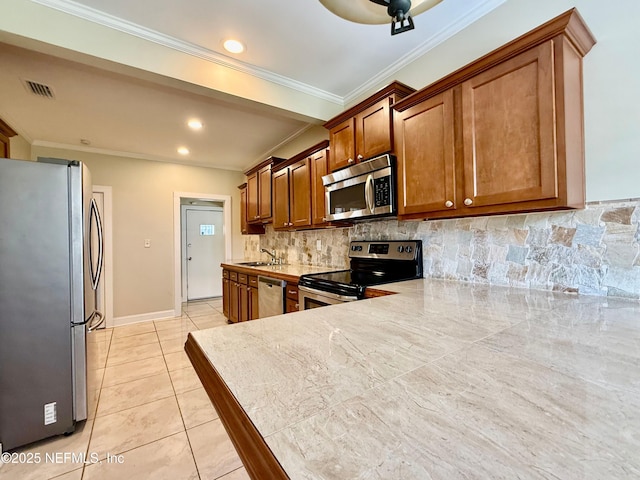 4518 Astral St, Jacksonville, FL 32205 - kitchen with appliances with stainless steel finishes, tasteful backsplash, ornamental molding, brown cabinets, and light tile patterned floors