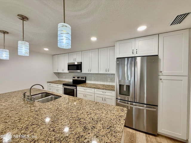 4518 Astral St, Jacksonville, FL 32205 - kitchen featuring stainless steel appliances, white cabinets, light stone countertops, recessed lighting, and a textured ceiling