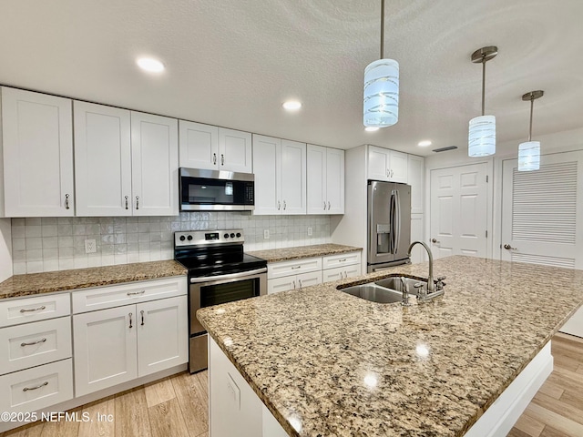 4518 Astral St, Jacksonville, FL 32205 - kitchen featuring appliances with stainless steel finishes, white cabinetry, light wood-type flooring, a kitchen island with sink, and recessed lighting