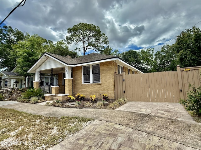 4518 Astral St, Jacksonville, FL 32205 - view of front facade featuring a porch, brick siding, a gate, and driveway