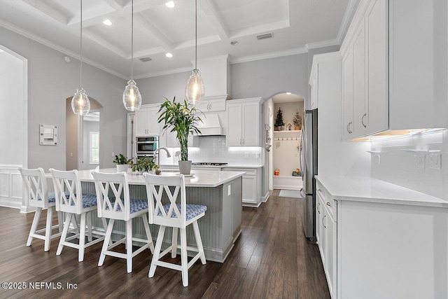 195 Glenneyre Cir, Saint Augustine, FL 32092 - kitchen with arched walkways, a center island with sink, appliances with stainless steel finishes, white cabinetry, and beamed ceiling