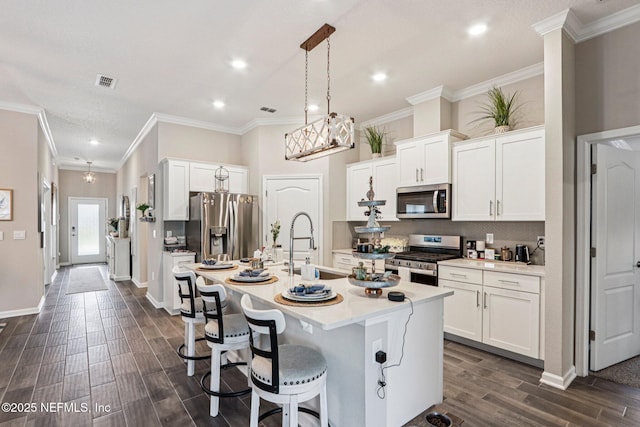 44 Spotted Owl Ln, Saint Augustine, FL 32095 - kitchen with stainless steel appliances, dark wood-style flooring, an island with sink, light countertops, and crown molding