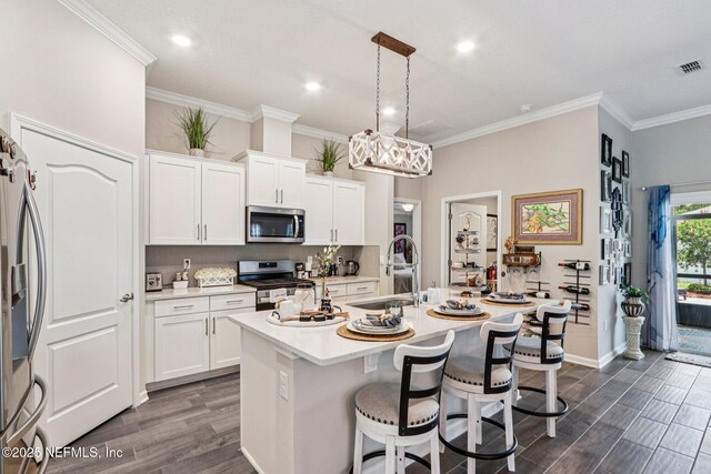 44 Spotted Owl Ln, Saint Augustine, FL 32095 - kitchen with appliances with stainless steel finishes, dark wood-style floors, decorative backsplash, a breakfast bar area, and ornamental molding