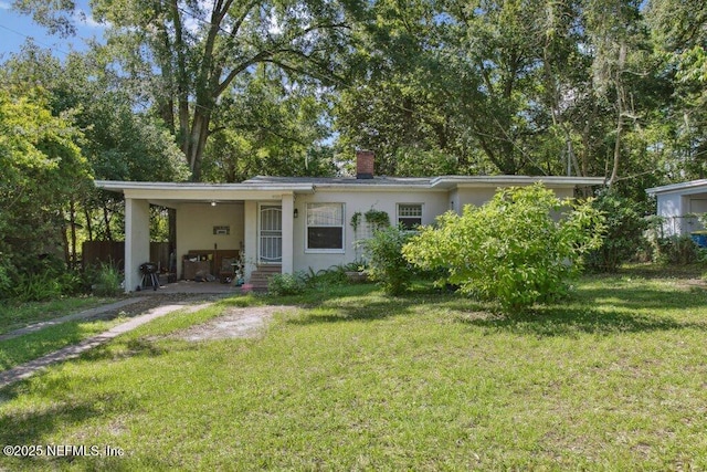 950 Ashton St, Jacksonville, FL 32208 - view of front of home featuring a front lawn, stucco siding, a chimney, and an attached carport