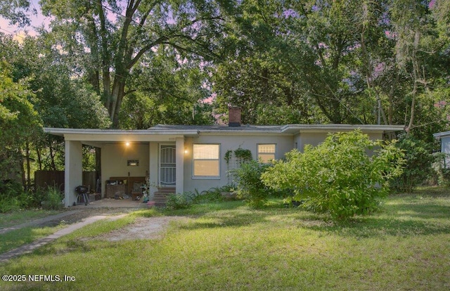 950 Ashton St, Jacksonville, FL 32208 - view of front of home with a front yard, a carport, a chimney, and stucco siding