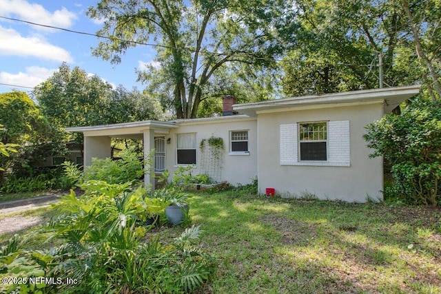 950 Ashton St, Jacksonville, FL 32208 - view of front facade featuring stucco siding, a front lawn, and a chimney