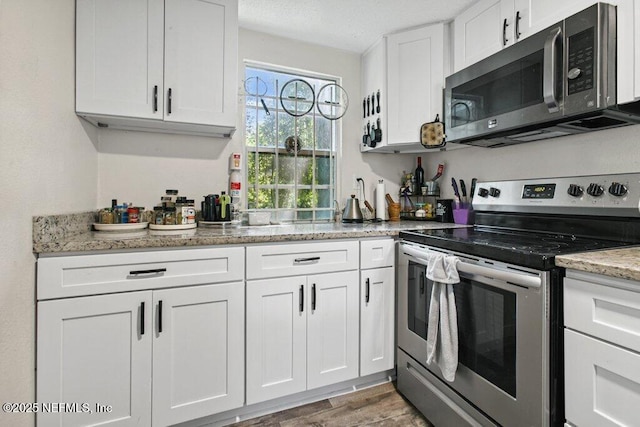 950 Ashton St, Jacksonville, FL 32208 - kitchen with appliances with stainless steel finishes, white cabinetry, wood finished floors, and light stone countertops