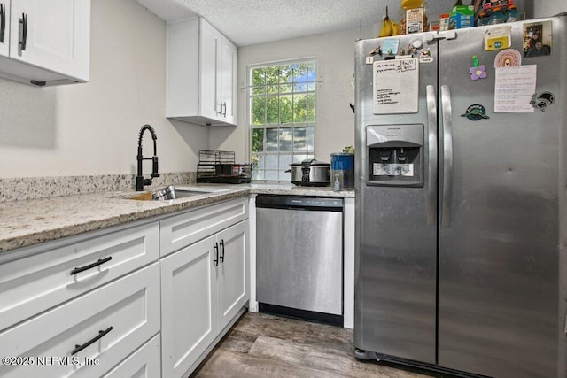 950 Ashton St, Jacksonville, FL 32208 - kitchen with appliances with stainless steel finishes, white cabinets, light wood-style flooring, and a textured ceiling