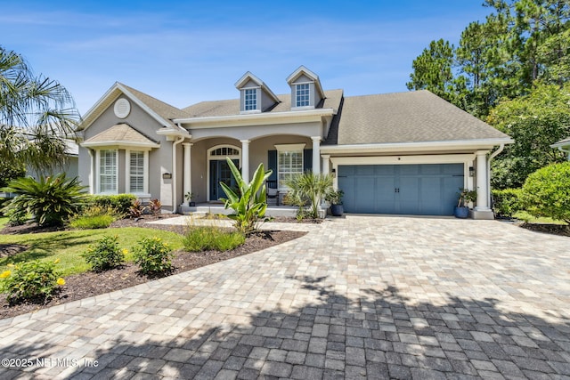 95006 Buckeye Ct, Fernandina Beach, FL 32034 - view of front facade featuring covered porch, stucco siding, an attached garage, and decorative driveway