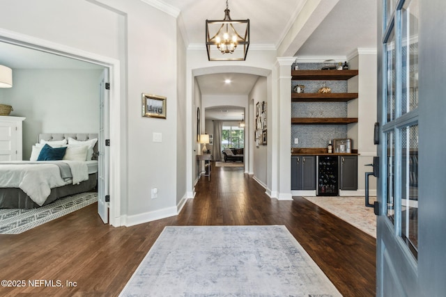 95006 Buckeye Ct, Fernandina Beach, FL 32034 - foyer with arched walkways, beverage cooler, dark wood-style floors, a chandelier, and crown molding