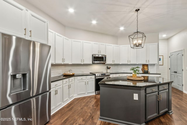95006 Buckeye Ct, Fernandina Beach, FL 32034 - kitchen featuring stainless steel appliances, tasteful backsplash, a center island, dark stone countertops, and dark wood-type flooring