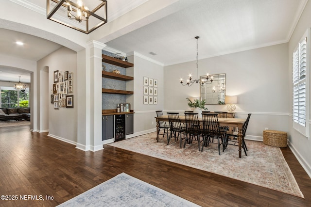 95006 Buckeye Ct, Fernandina Beach, FL 32034 - dining space featuring a chandelier, beverage cooler, wood finished floors, arched walkways, and ornamental molding