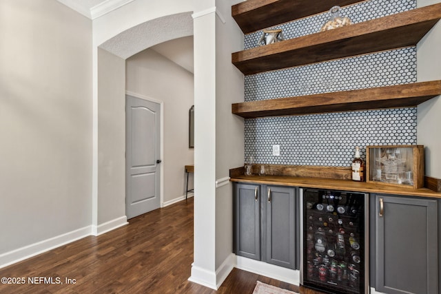95006 Buckeye Ct, Fernandina Beach, FL 32034 - indoor dry bar featuring beverage cooler, arched walkways, crown molding, and dark wood-type flooring