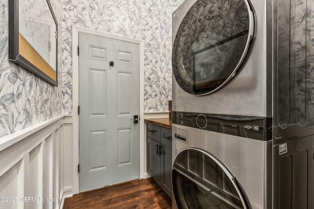 95006 Buckeye Ct, Fernandina Beach, FL 32034 - washroom featuring estacked washer and dryer, wallpapered walls, cabinet space, and dark wood-style flooring
